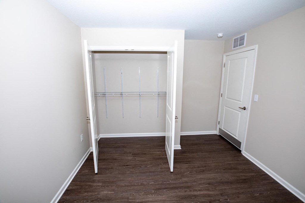 a room with a closet and a wooden floor and a white door