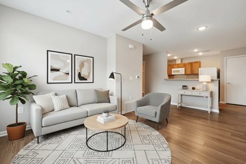 A living room with a grey couch, a grey armchair, a coffee table, and a ceiling fan.