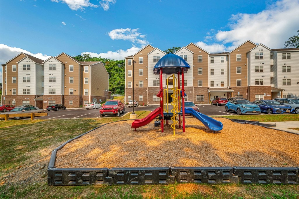 a playground with a blue and red slide in front of an apartment building