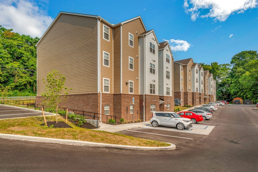 a row of apartment buildings with cars parked in a parking lot