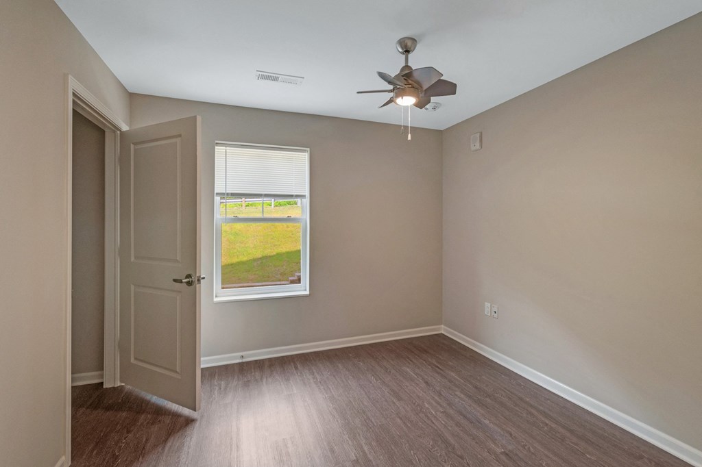 an empty bedroom with a window and a ceiling fan