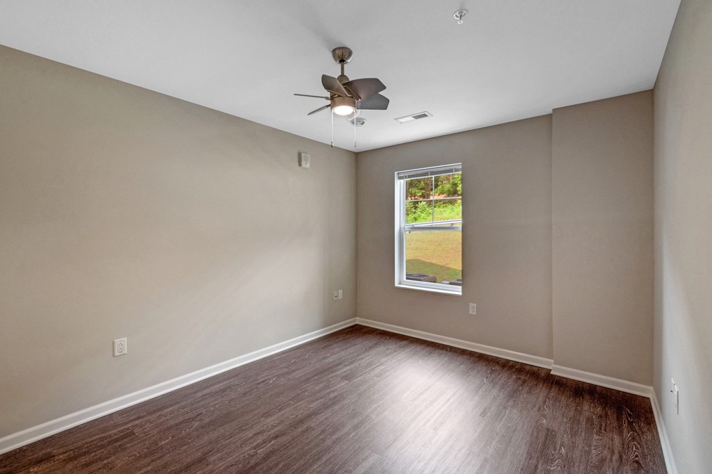 an empty living room with wood floors and a ceiling fan