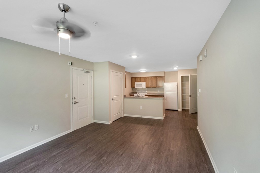 an empty living room and kitchen with a ceiling fan