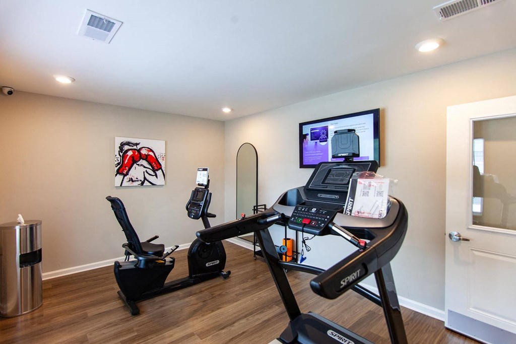 a home gym with a treadmill and a tv on the wall