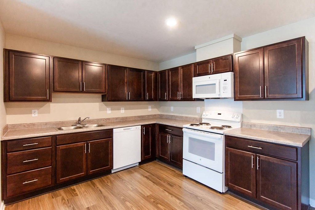 a kitchen with dark wood cabinets and white appliances