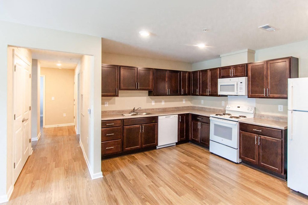 a large kitchen with wooden floors and white appliances