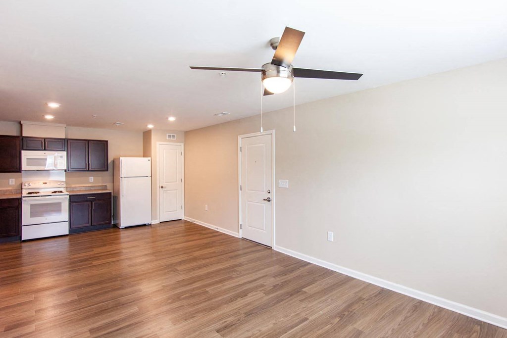 a living room with a kitchen and a ceiling fan