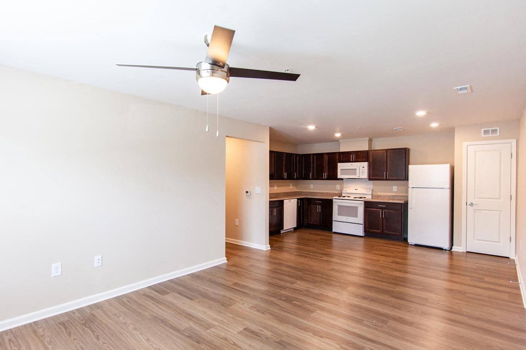 a living room and kitchen with wood floors and a ceiling fan