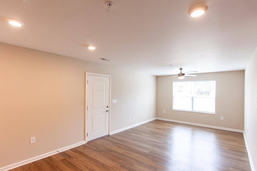 a living room with wood floors and a white door and a window