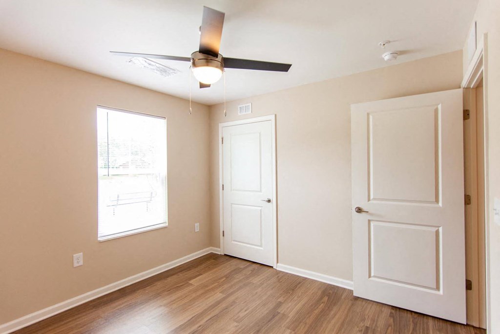 an empty bedroom with a ceiling fan and a window