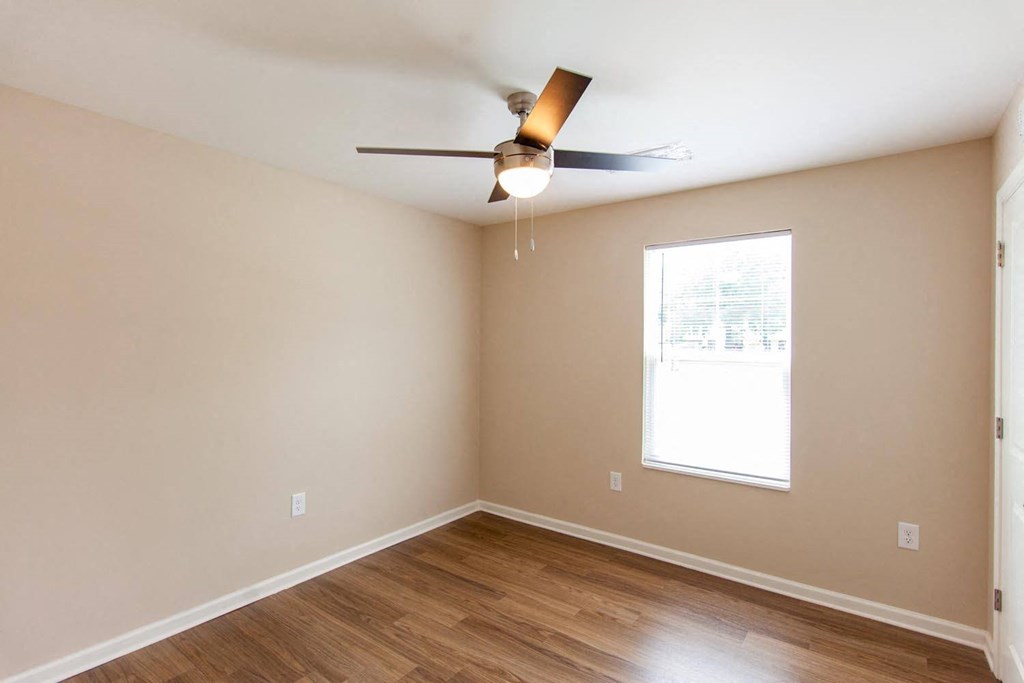 an empty living room with a ceiling fan and a window