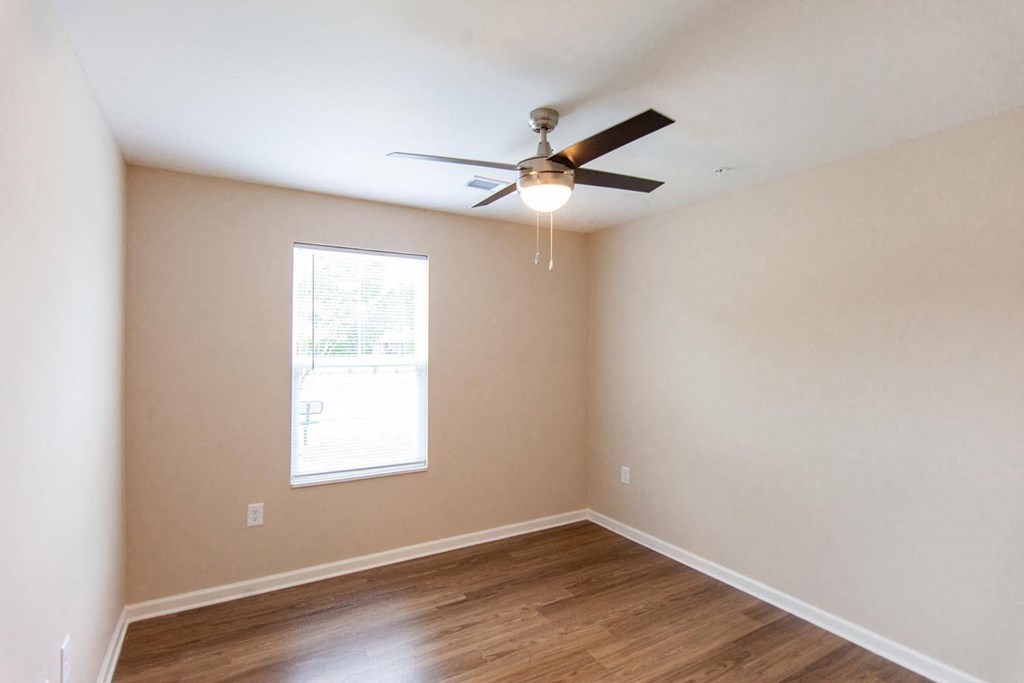 an empty living room with a ceiling fan and a window