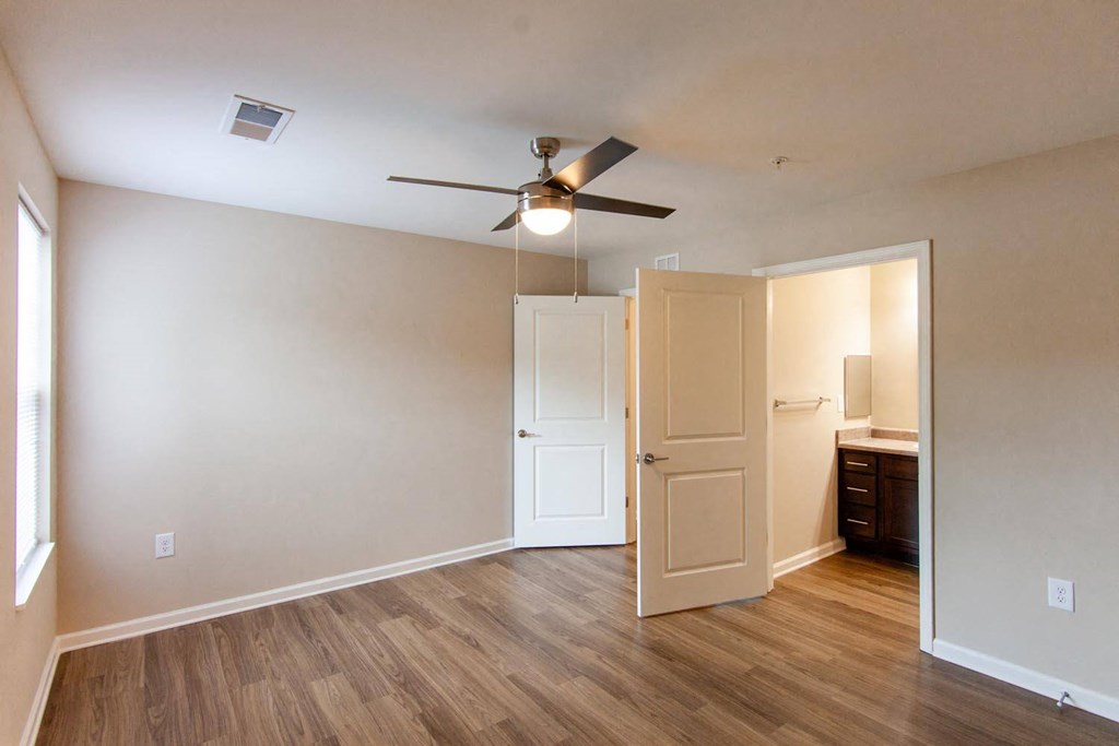 an empty living room with a ceiling fan and a closet