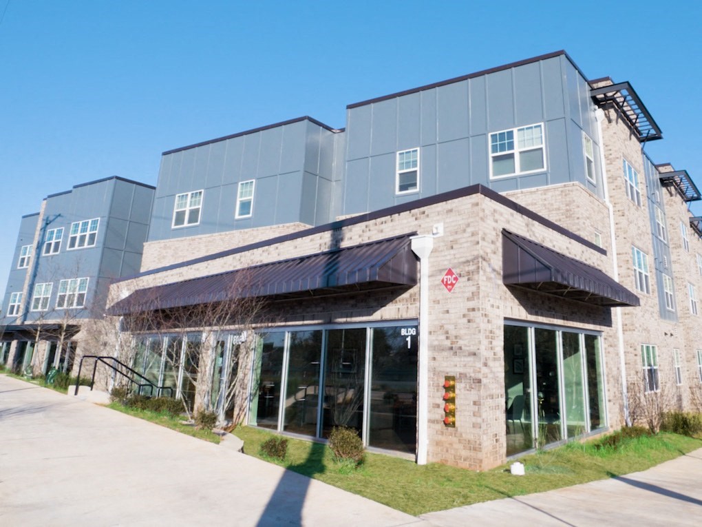 the front of a building with glass windows and a sidewalk