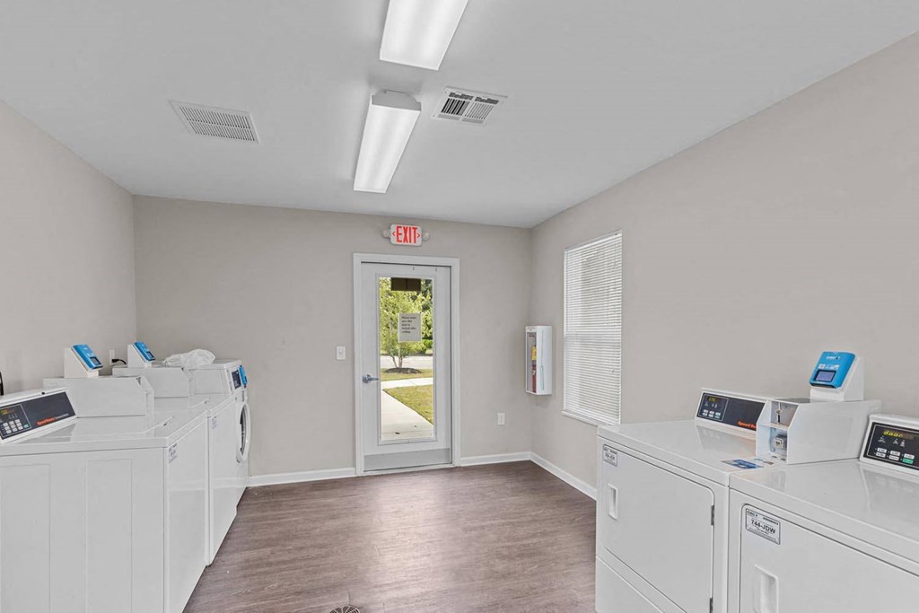 a laundry room with washers and dryers and a door to a hallway