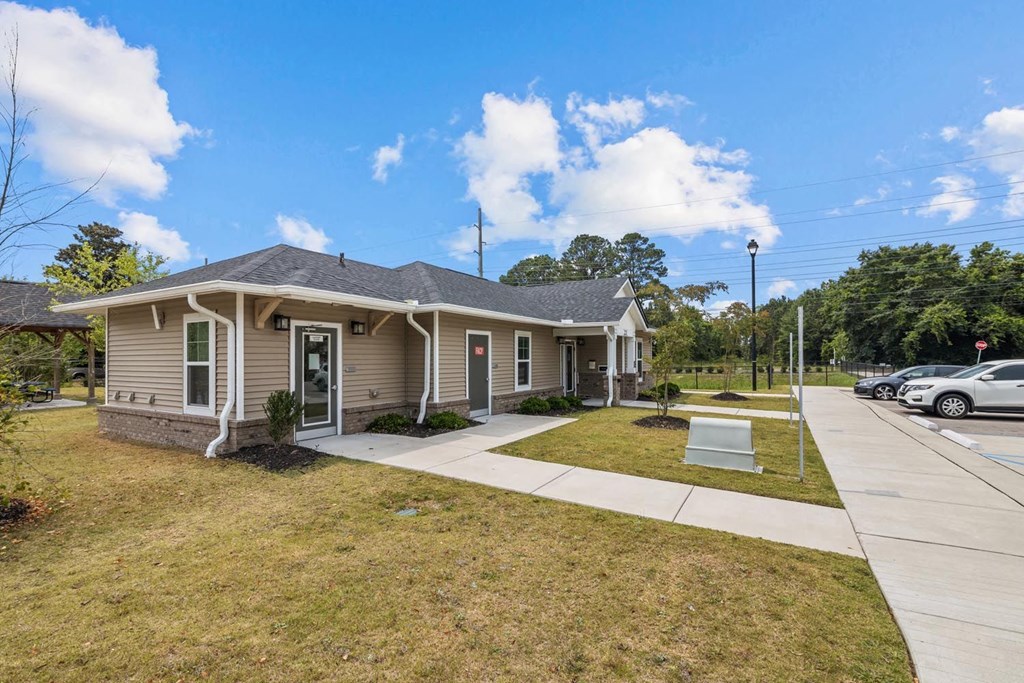 a beige house with a sidewalk and cars parked in front of it