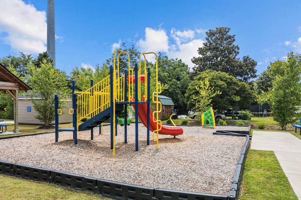 a playground at a park with a yellow and red swing set