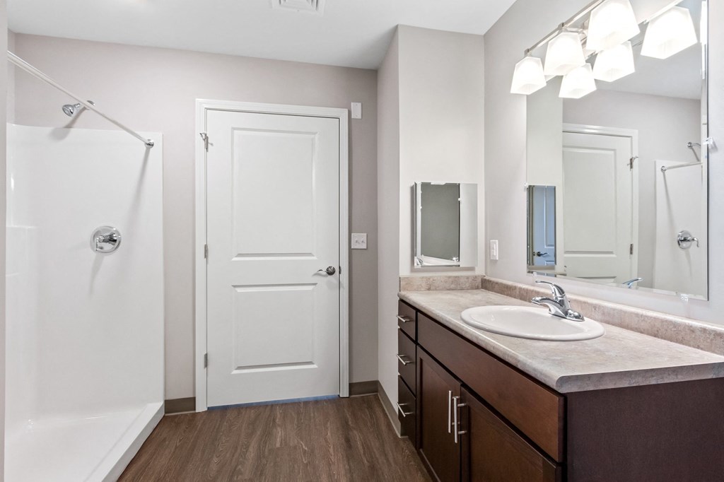 a bathroom with a sink and a shower and a mirror