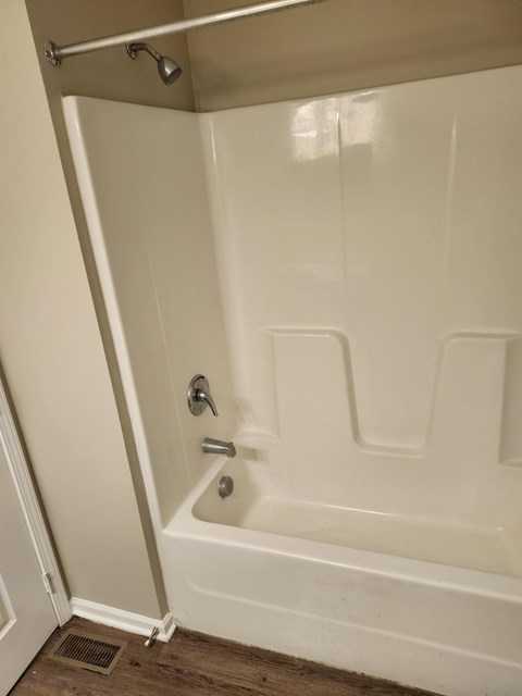 A white bathtub with a silver faucet and a silver shower head.