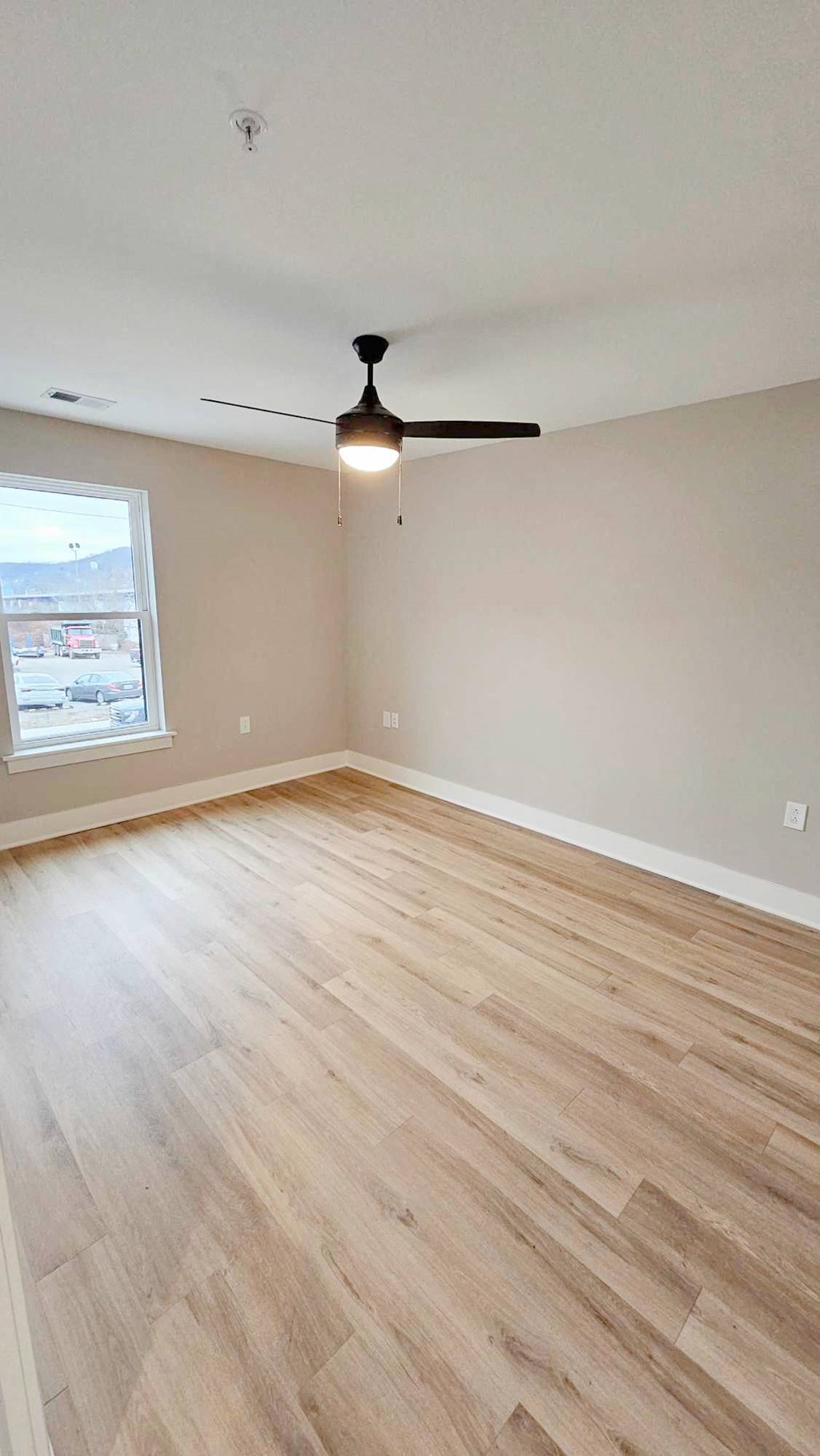 an empty living room with wood flooring and a ceiling fan