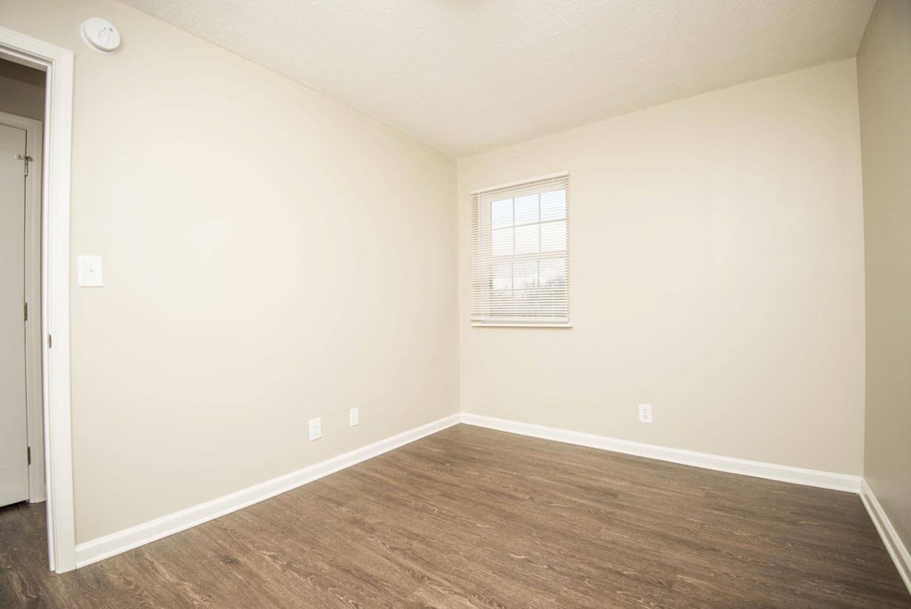 a room with white walls and wood floors and a window