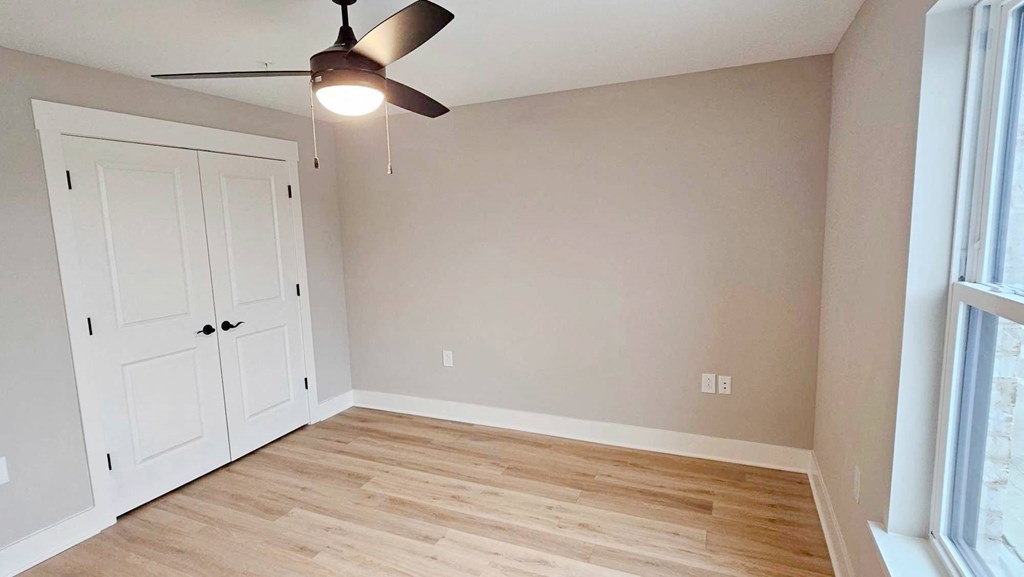 an empty living room with a ceiling fan and a closet