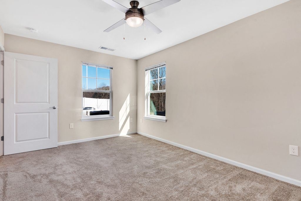 an empty living room with a ceiling fan and a window