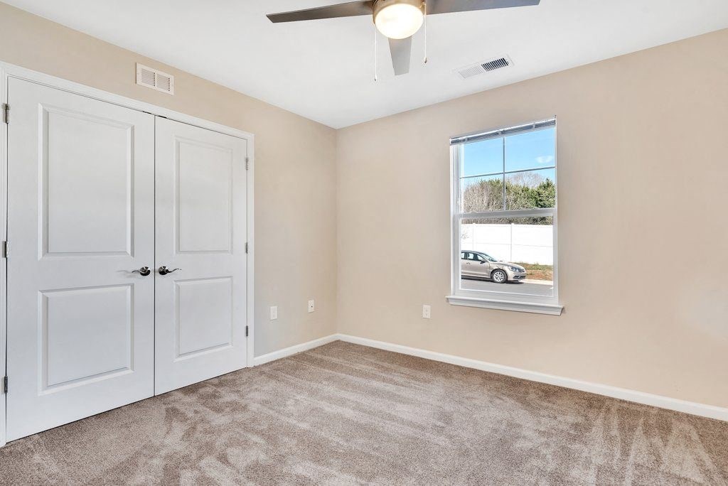 an empty bedroom with a window and a closet