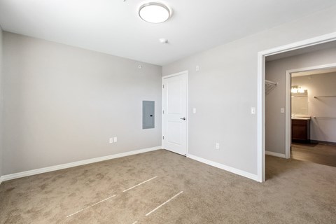 an empty living room with carpet and a door to a bathroom