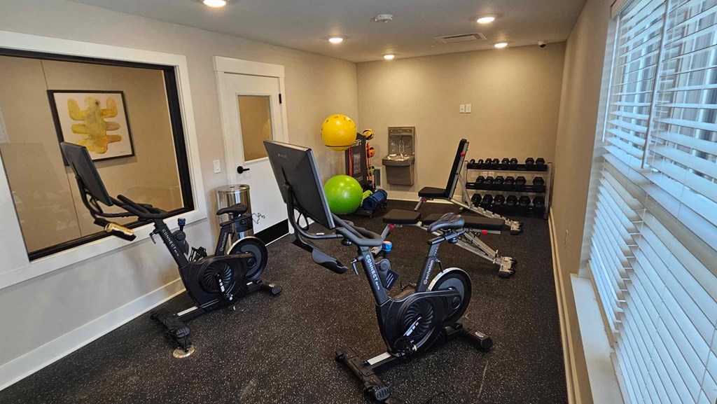 a home gym with exercise bikes and a yellow ball on the floor