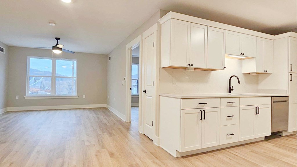 an empty kitchen with white cabinets and a window