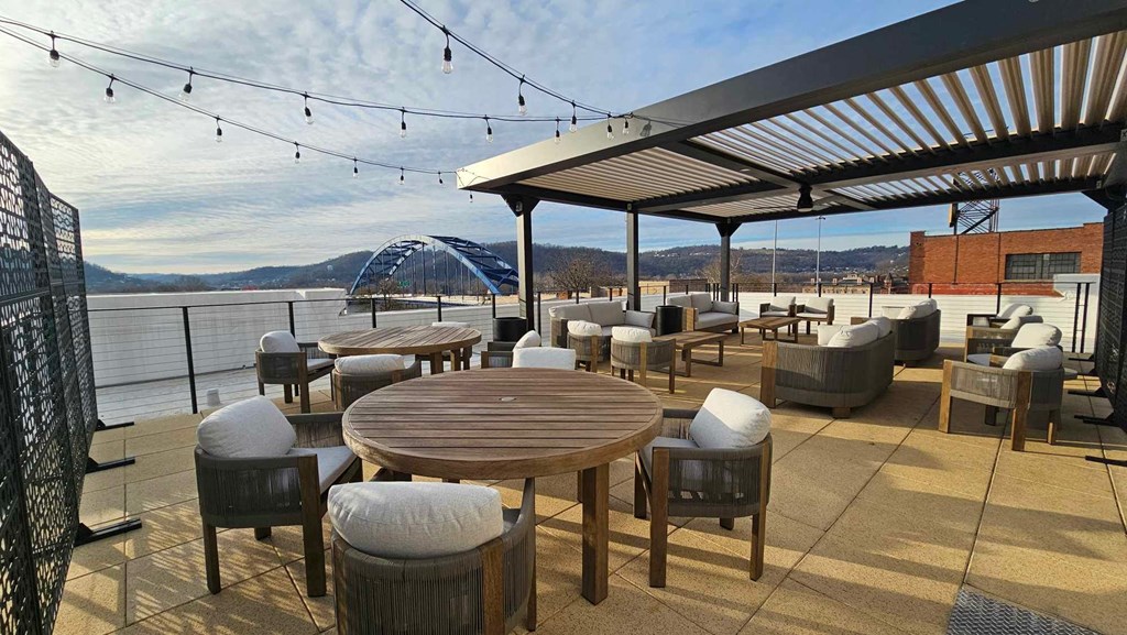 the deck on the water has tables and chairs and a pergola