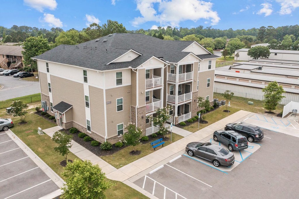 an aerial view of an apartment building with cars parked in a parking lot