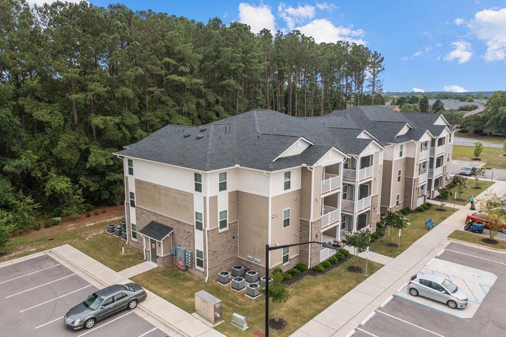 an aerial view of an apartment building with cars parked in a parking lot