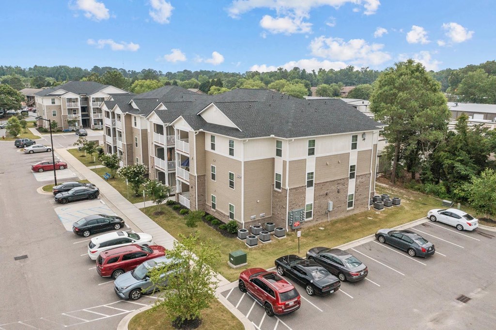 an aerial view of an apartment complex with cars parked in a parking lot