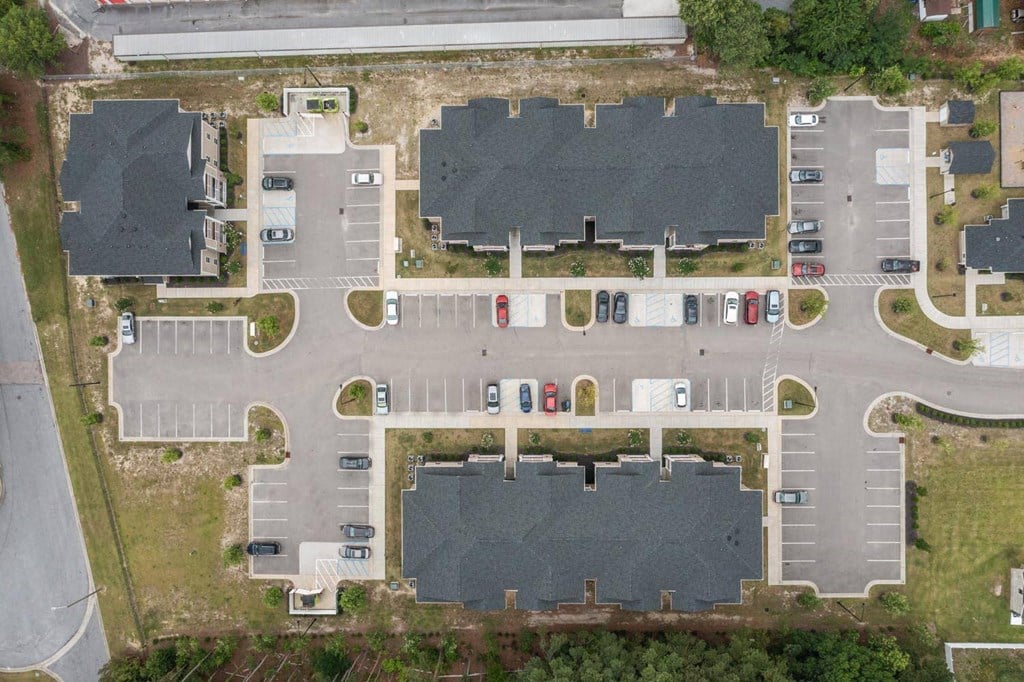 an aerial view of a parking lot with houses and cars