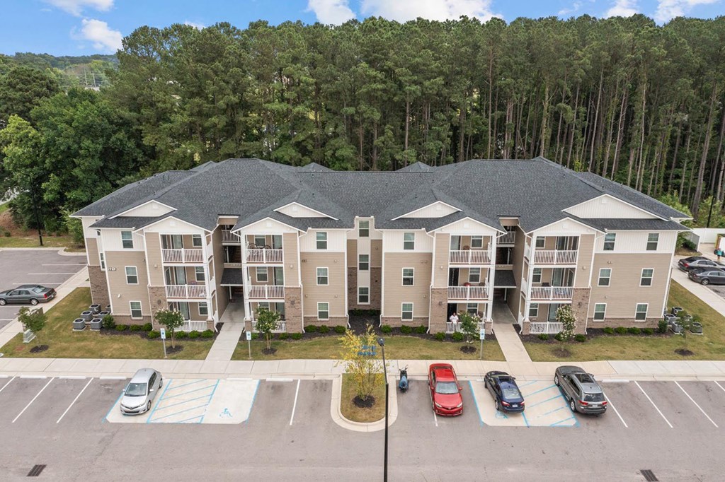 an aerial view of an apartment building with parking lot and trees