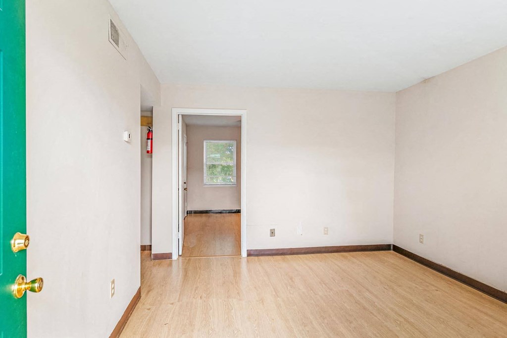 a bedroom with hardwood floors and white walls