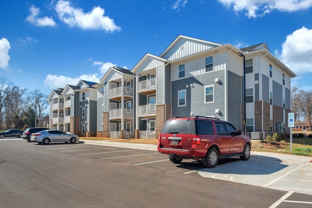 a red van parked in a parking lot in front of an apartment building