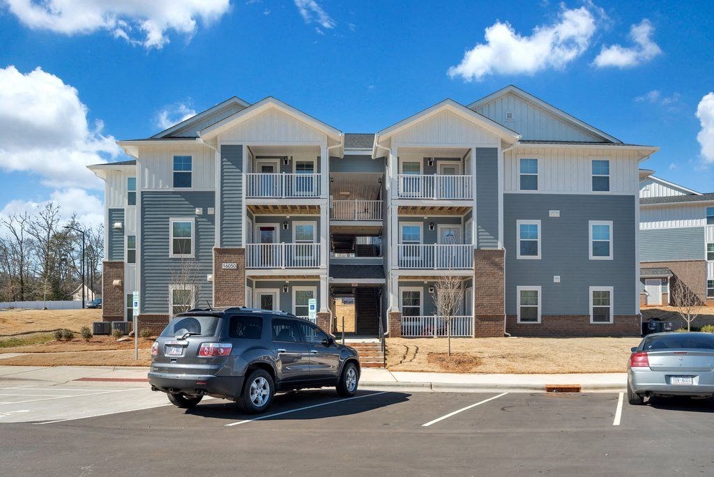 an apartment building with a car parked in a parking lot