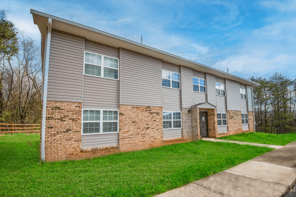 a brick and siding apartment building with a sidewalk and grass