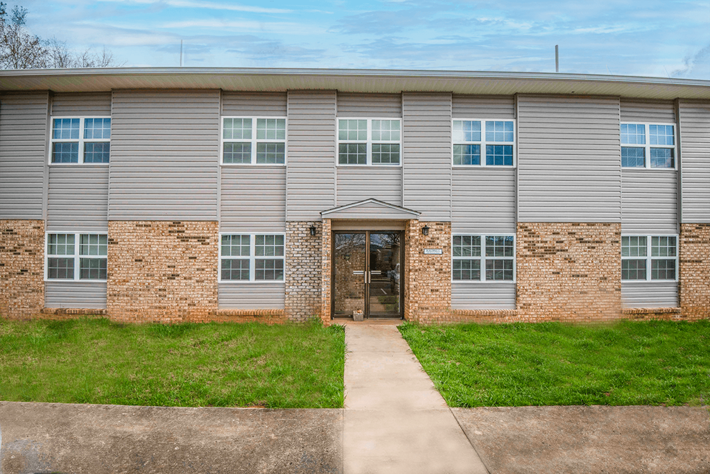 front view of an apartment building with a sidewalk and grass