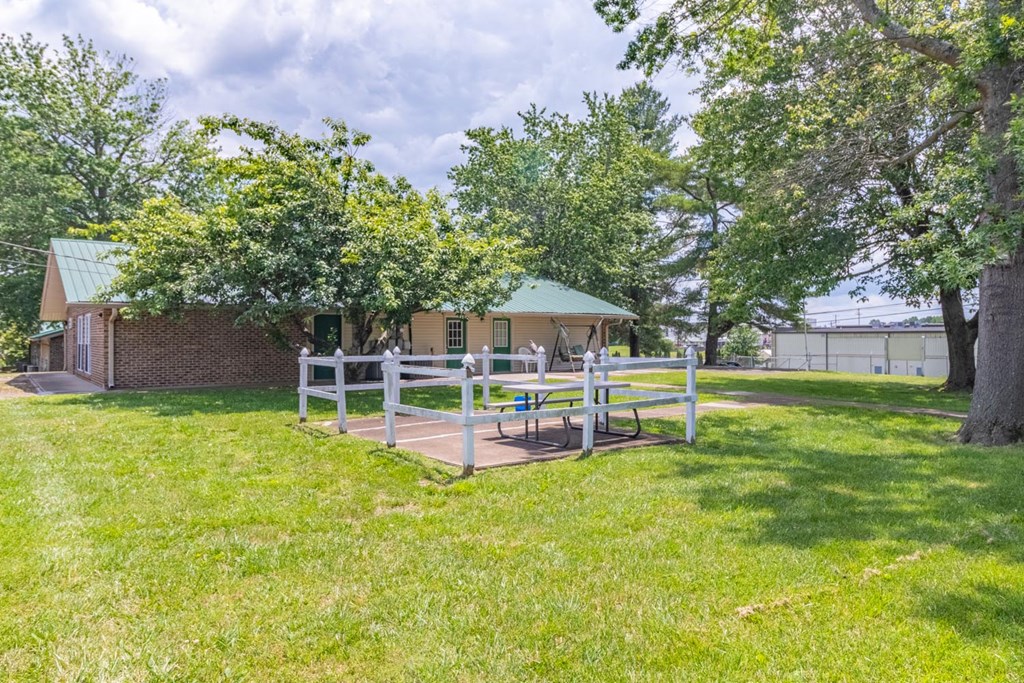 a fenced in area with a picnic table and chairs in front of a brick building