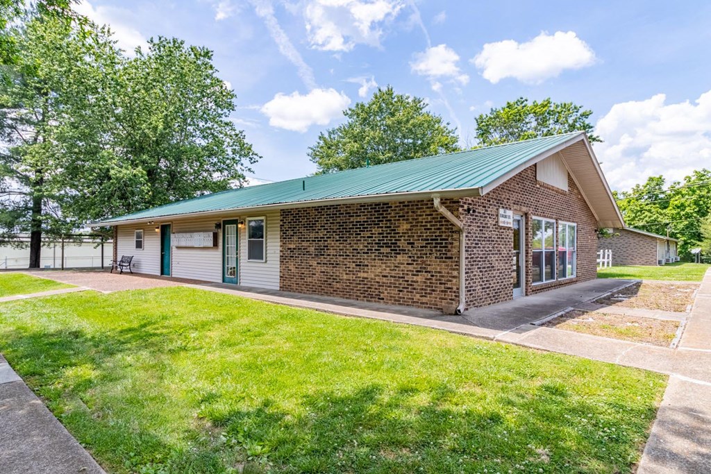 a brick building with a green roof and a lawn in front of it