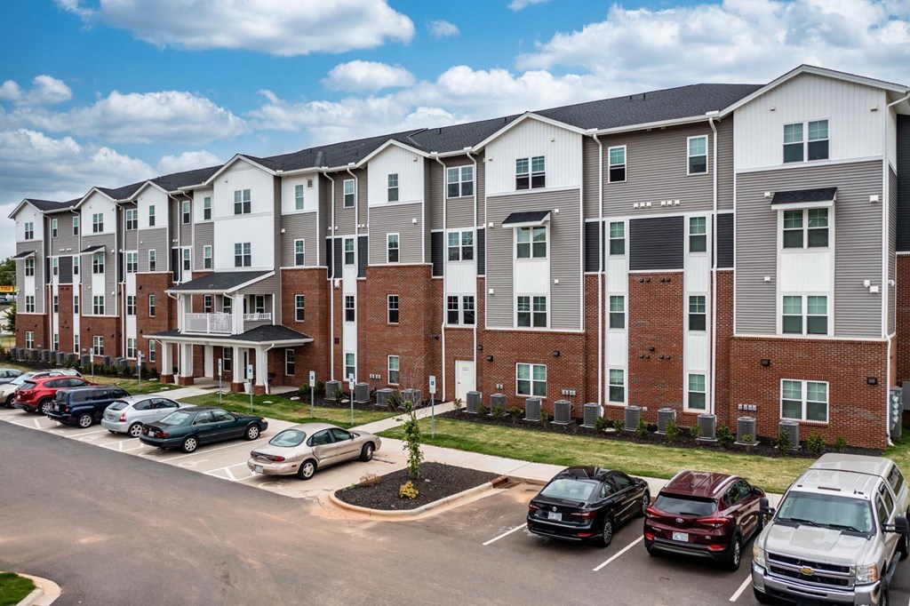 a row of apartment buildings with cars parked in front of them