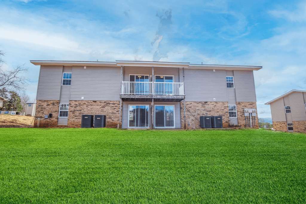 the back of a house with green grass in front of it