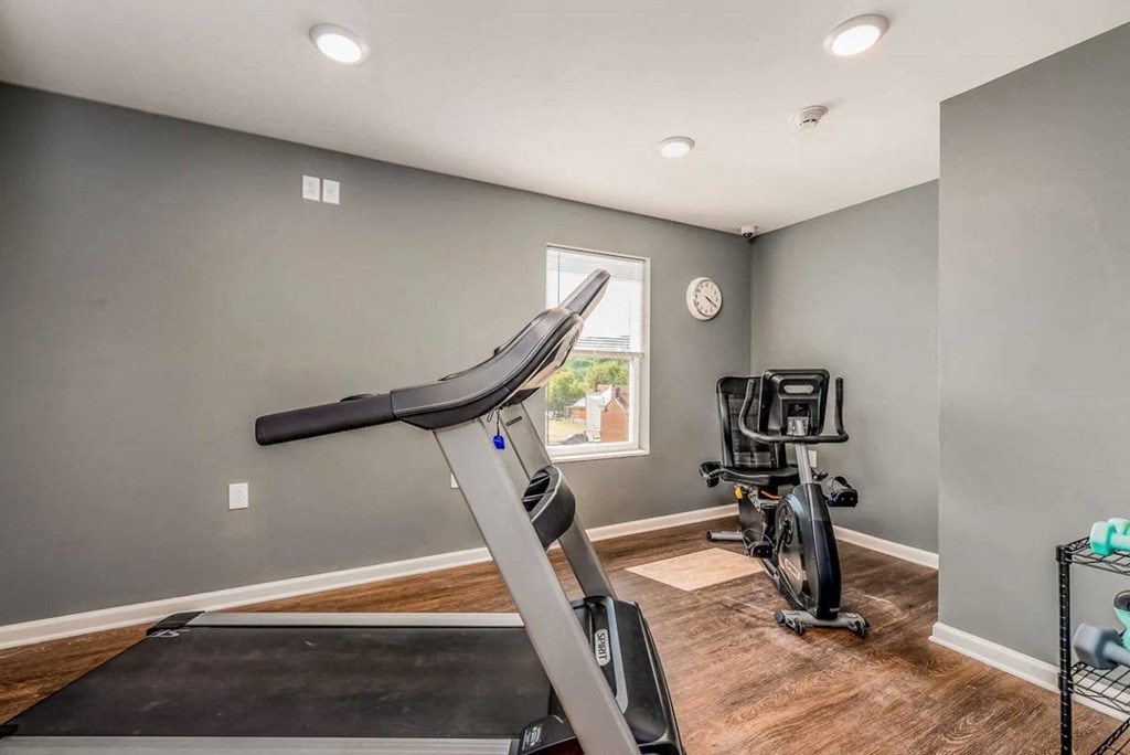 a gym with a treadmill and a bike in the corner