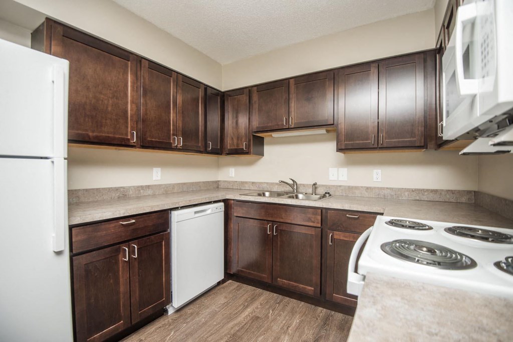 a kitchen with dark wood cabinets and white appliances
