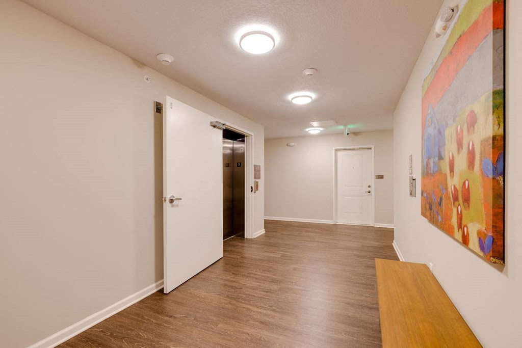 a long hallway with white walls and a large colorful painting on the wall