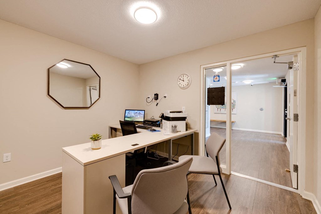 a desk with two chairs in a room with an open door